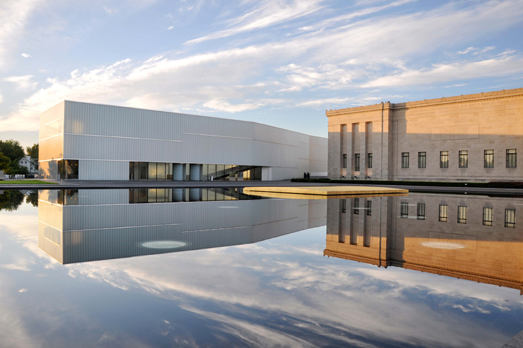 An early morning angled view of the Bloch Building on the left, the Nelson-Atkins Building on the right and the reflecting pool titled One Sun 34 Moons in the middle titled Get Involved Find your place at the Nelson-Atkins.