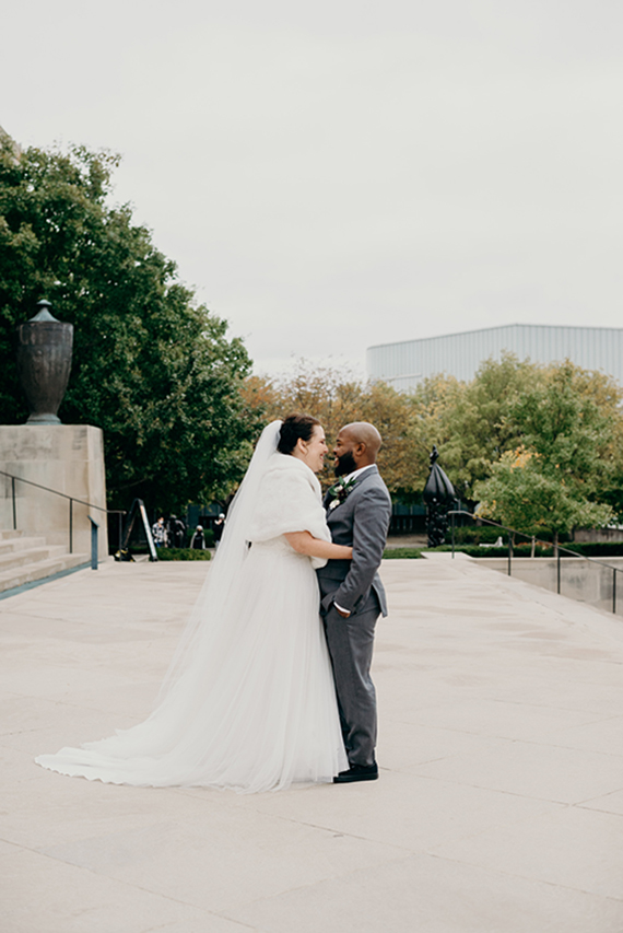 Just-married couple embracing on platform in front of south side of Nelson-Atkins Building