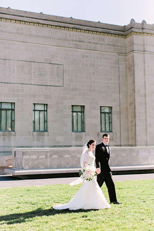 Just-married couple walking across the lawn on the north side of the Nelson-Atkins building