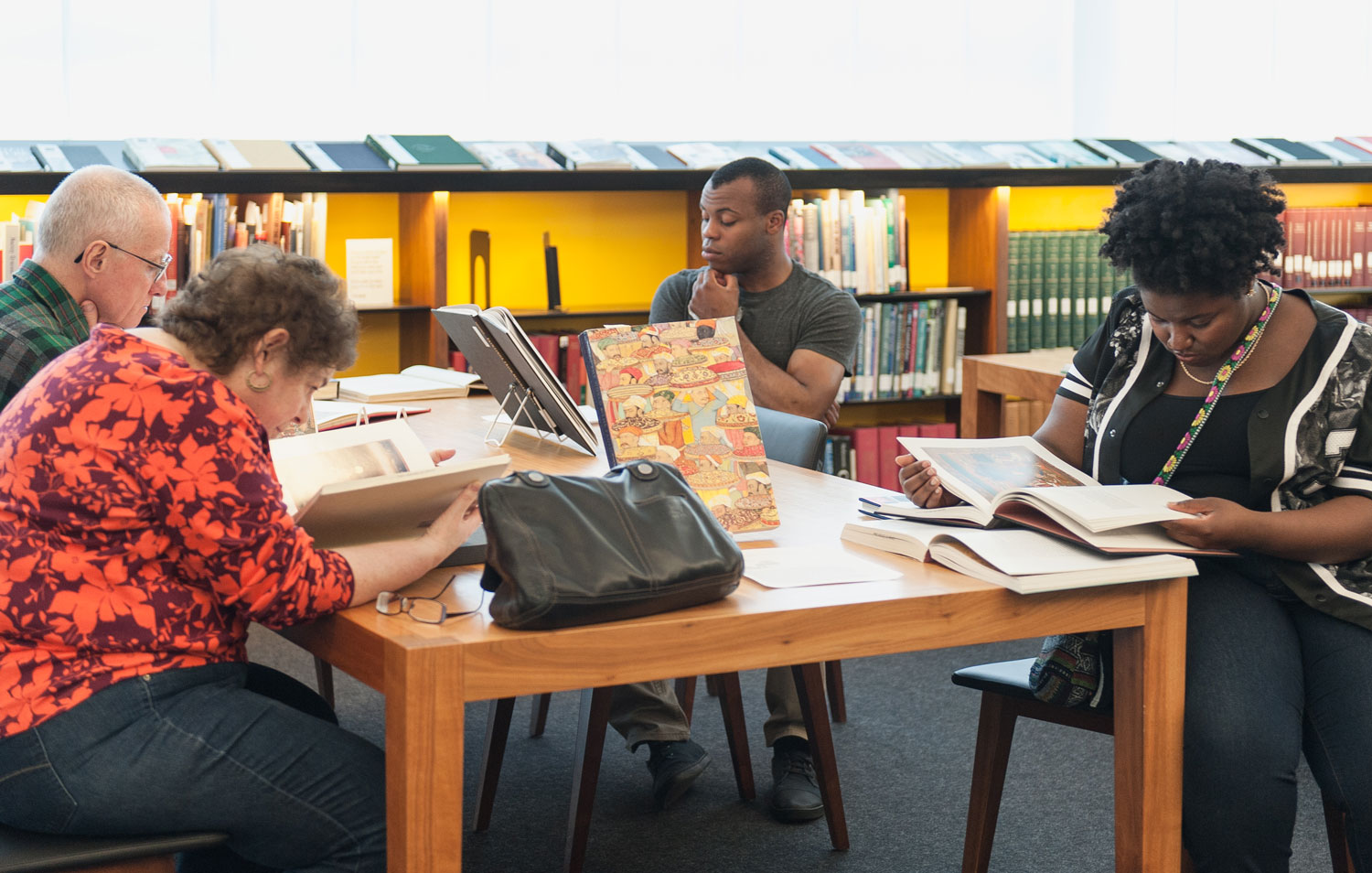 Four people sitting around a library table reading