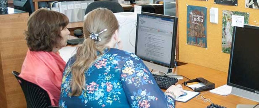 Two people sitting at a desk working with computer