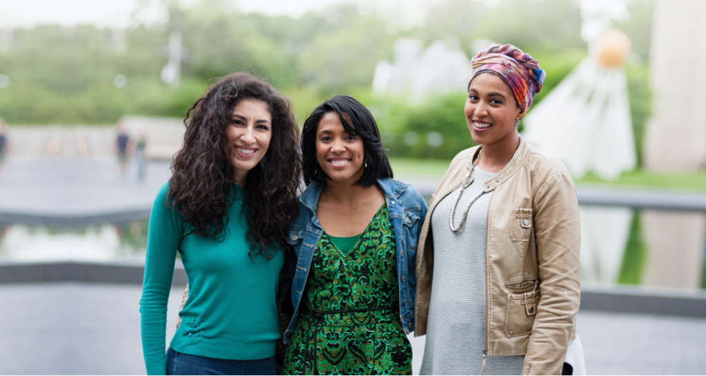 Three women stand in front of the shuttlecock sculpture on the Nelson-Atkins lawn