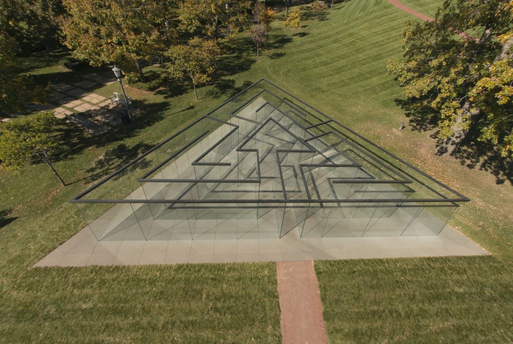 Guests explore inside and around the triangular glass labyrinth structure in the museum's Sculpture Park.