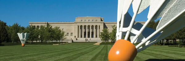 View from the South Lawn of The Nelson-Atkins Museum of Art showing the front facade with columns and 2 of the Shuttlecock sculptures