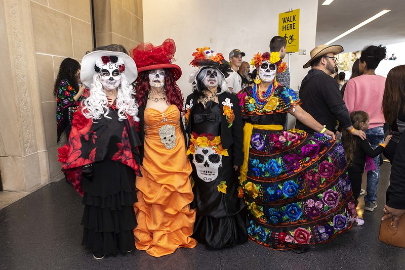 A group of women dressed up in traditional Dia de los Muertos colorful dresses and facepaint.