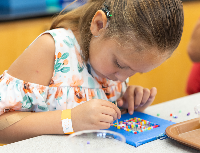Image of child creating beaded artwork