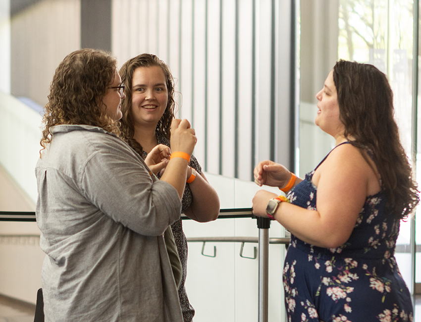 Image of three people talking and signing in gallery space