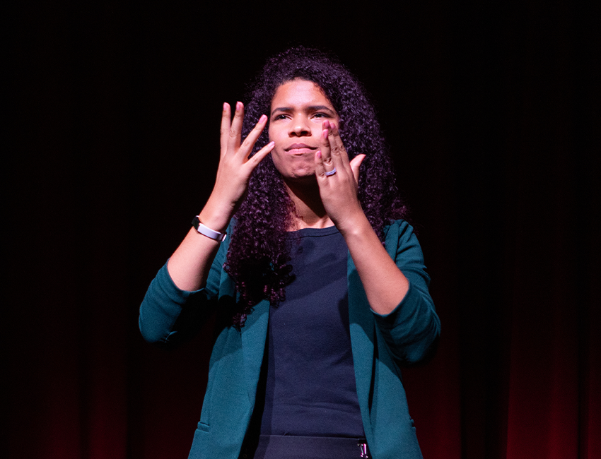 Image of person on stage signing.
