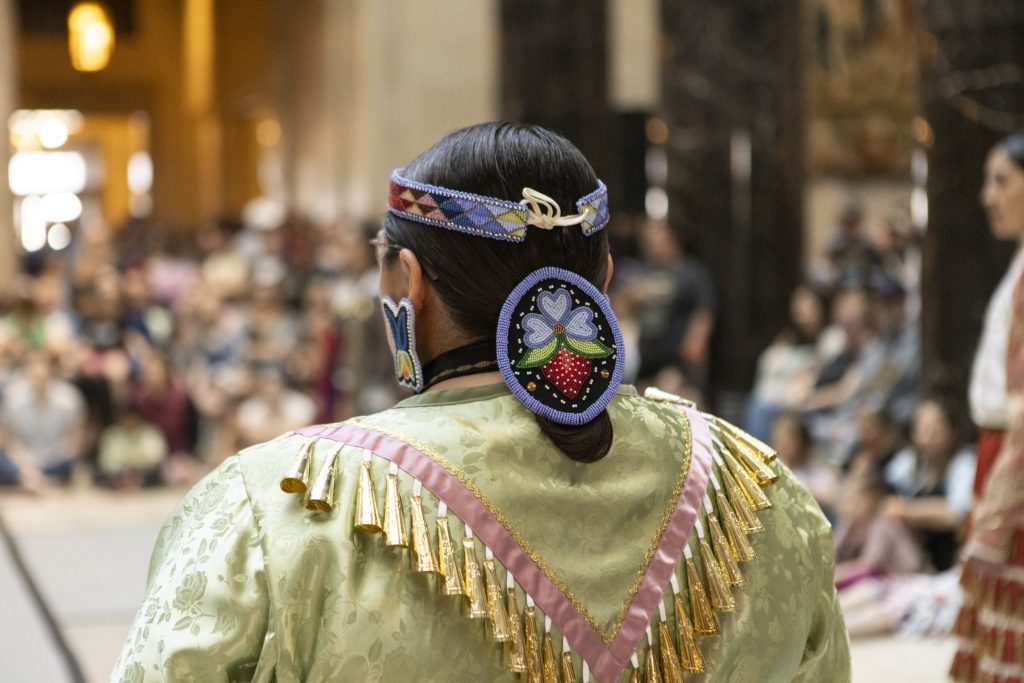 The back of a person's head showing beaded hair pieces and traditional native american dress