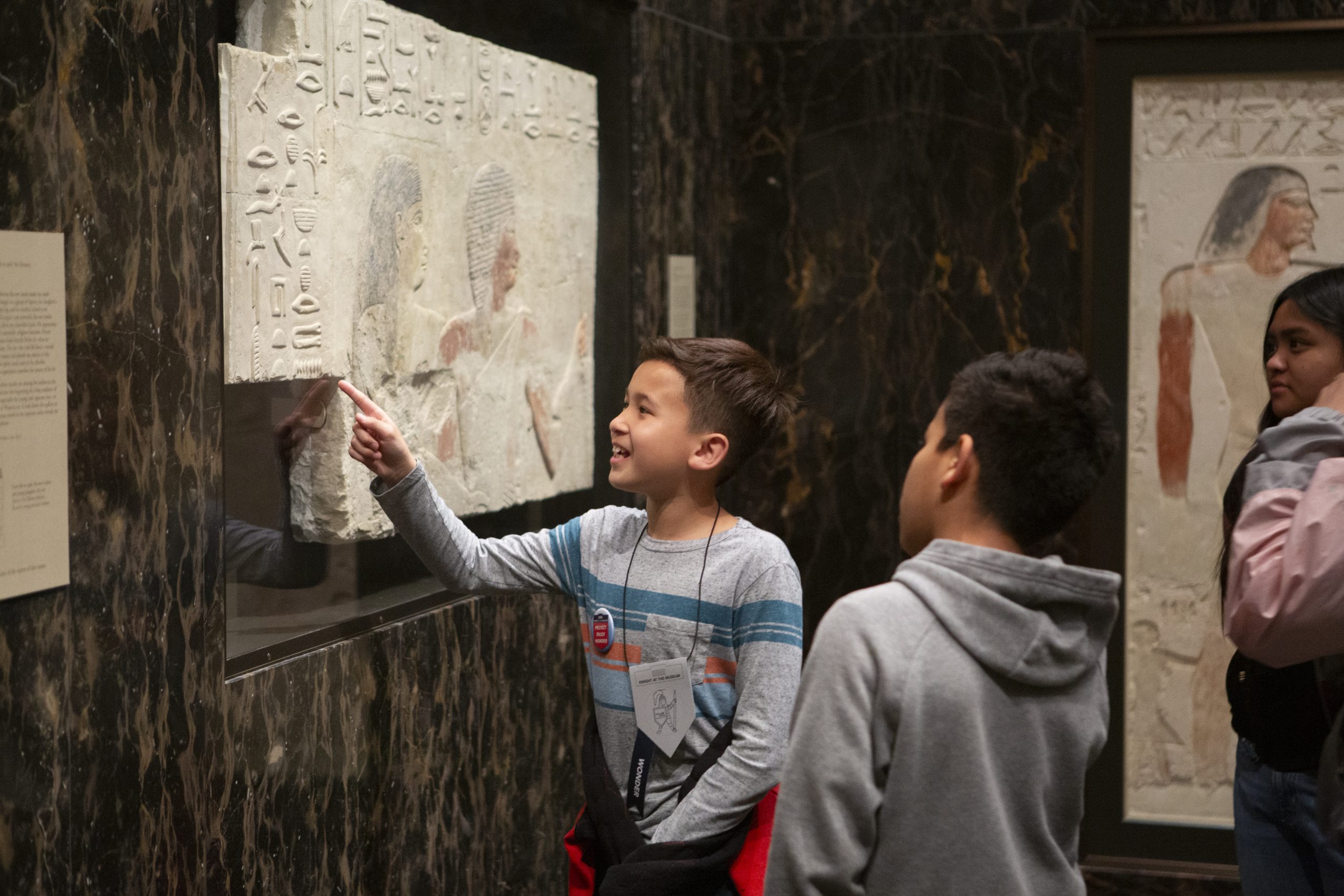 Two young people point at a work of art in the Egyptian gallery of The Nelson-Atkins Museum of Art.