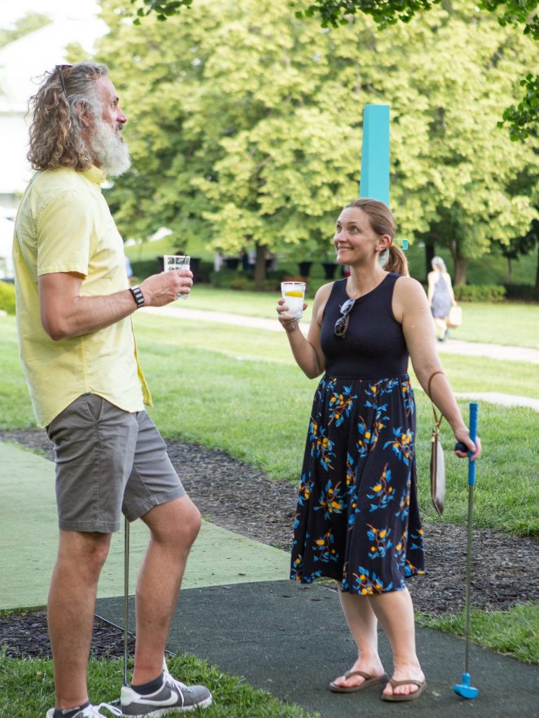 A man and woman chat over drinks at the Nelson-Atkins mini-golf Art Course.