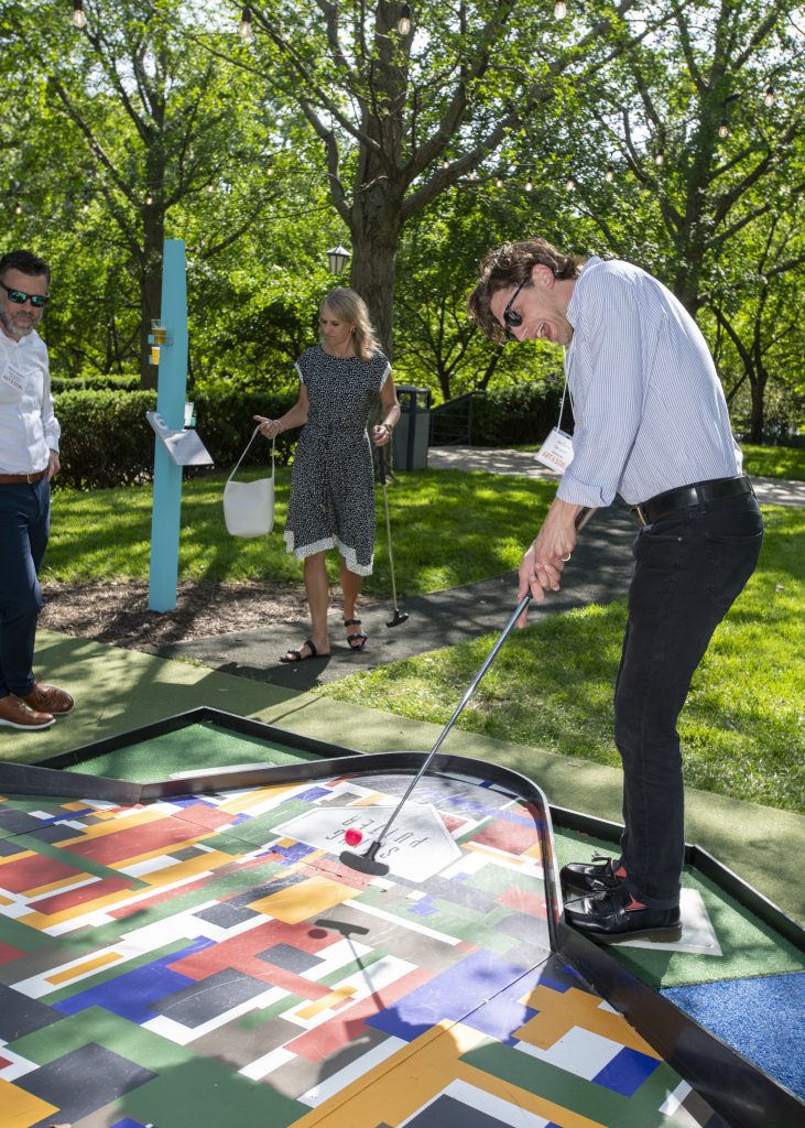 A man sinks a putt on at a private event on the Nelson-Atkins mini-golf Art Course.