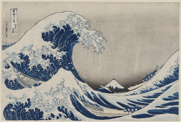 A blue wave with white foam crests with a mountain in the background