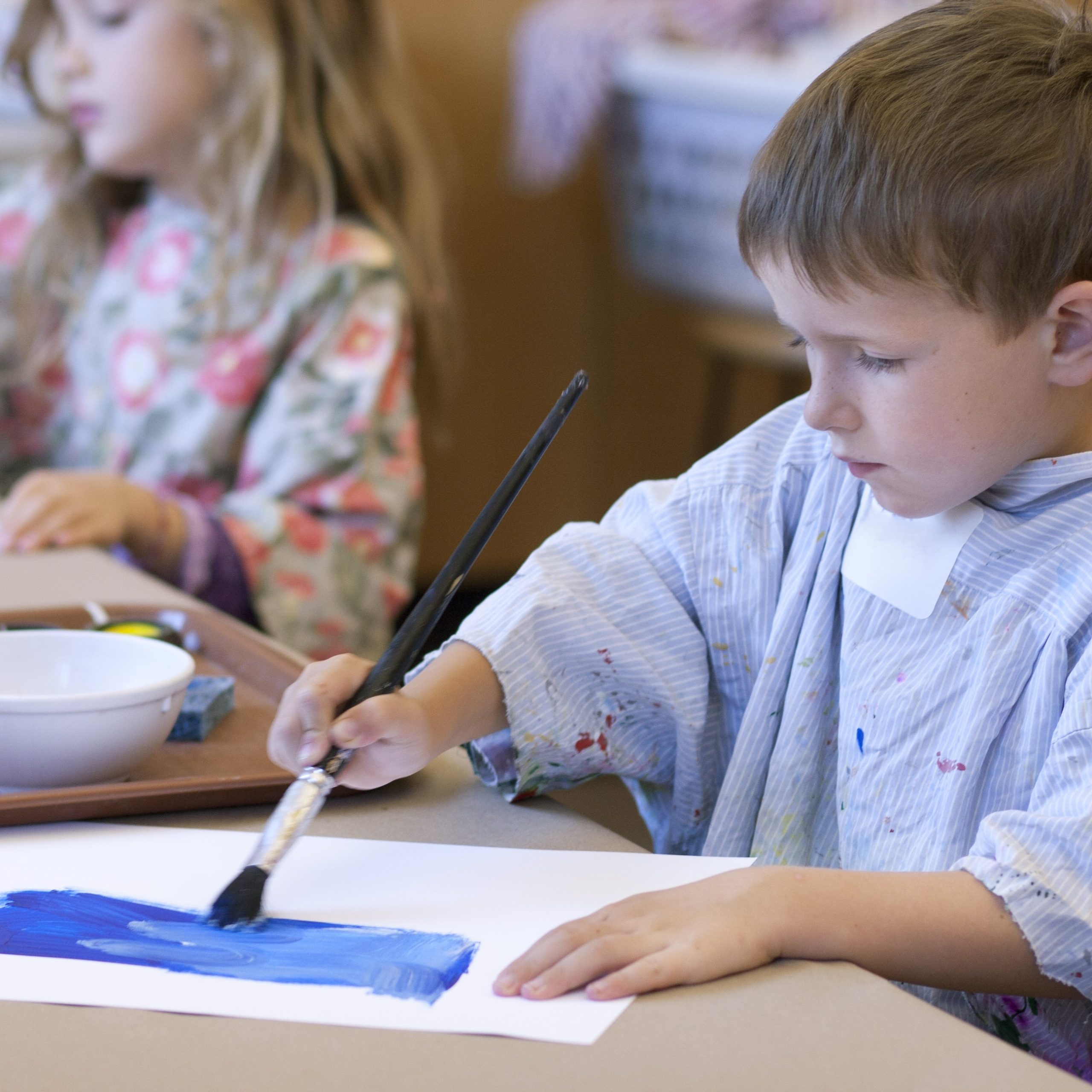 A person adjusting paintbrushes in their apron.