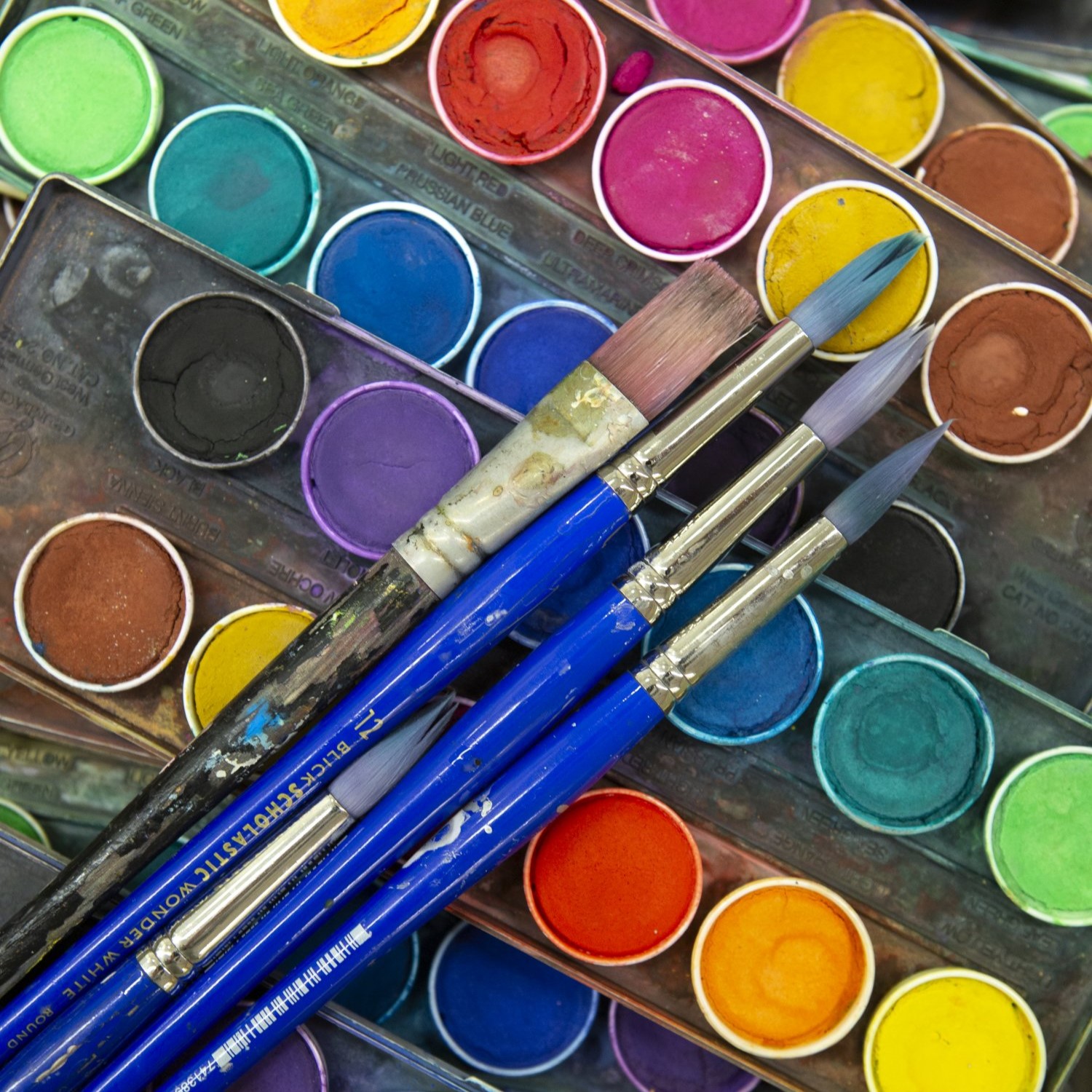 Art supplies ranging from scissors to colored pencils in varius cans.