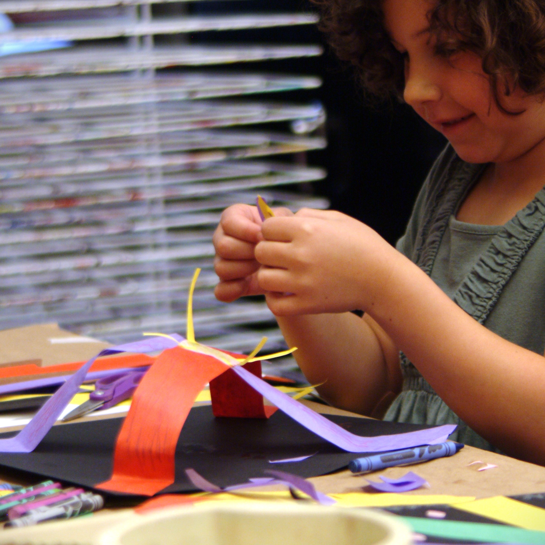 Multiple colors of pain on a table with pant brushes in them.