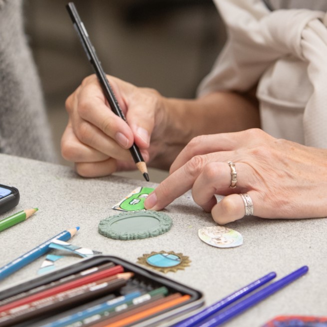 Multiple colors of pain on a table with pant brushes in them.