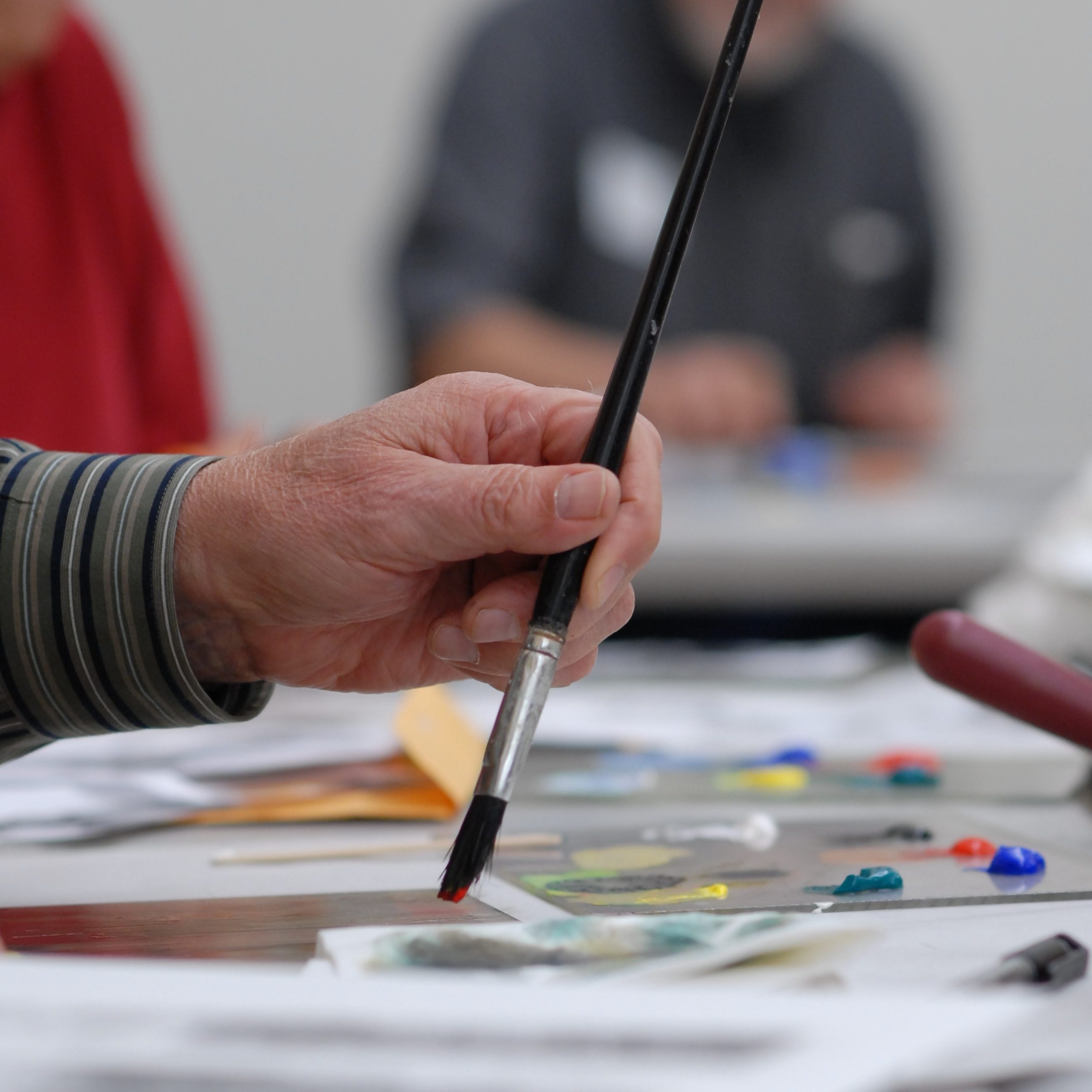 A person adjusting paintbrushes in their apron.