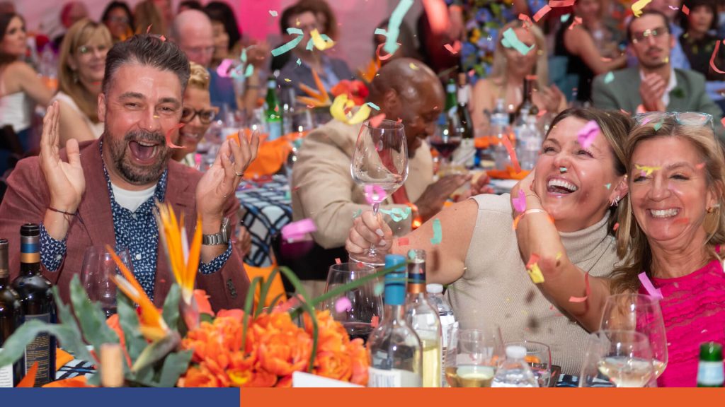 Group of three people clapping and laughing while confetti falls around them