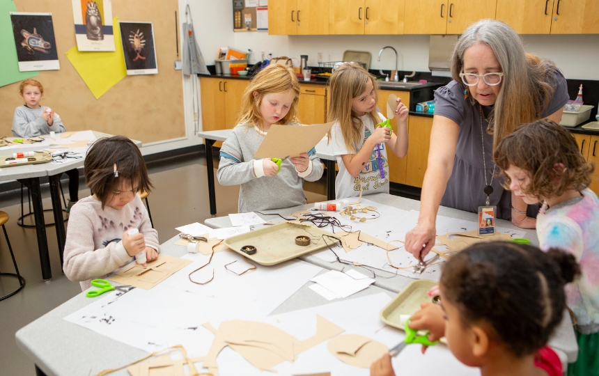 A person adjusting paintbrushes in their apron.