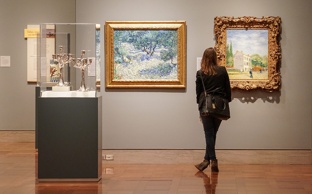 A woman stands in front of two impressionist paintings in the art gallery