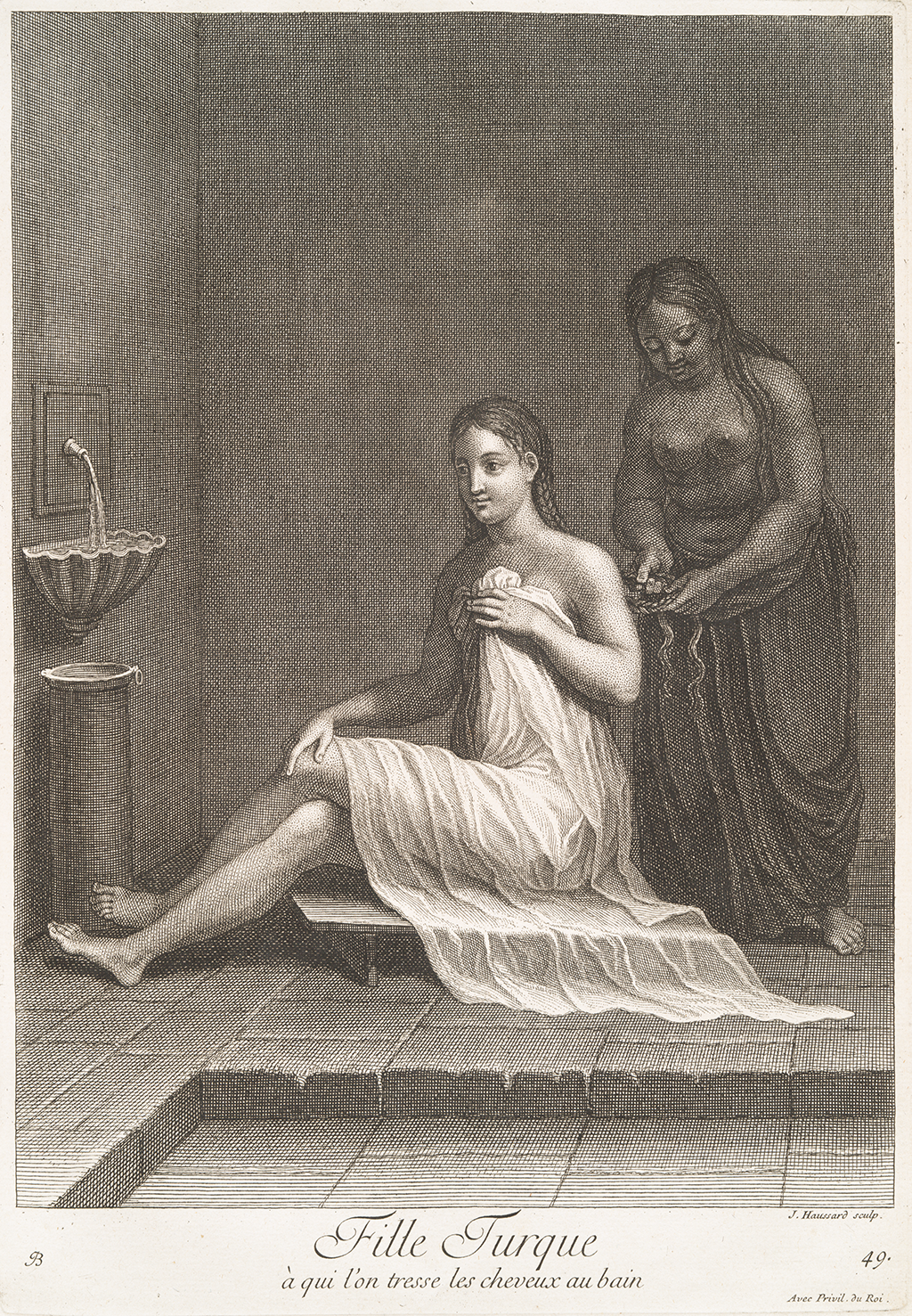 A black and white image of a lightly skinned woman sitting on a small wooden board, she covers herself with a large but loose fabric. Behind her is a darker skinned woman holding the lightly skinned woman’s hair. On the wall to the left, there is a stink with water pouring from a faucet. The text at the bottom says &ldquo;Fille Turque a qui l’on tresse les cheveux au bain.&rdquo;