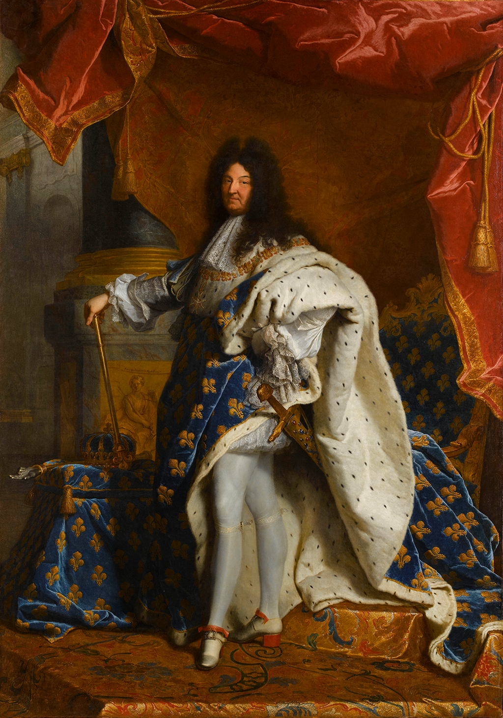 A full-length portrait of a man, standing with a golden scepter in his right hand, and his left hand on his hip. He wears a long blue cape with a gold fleur-de-lis pattern that is lined with white ermine fur which drapes over his left shoulder. The man has long curly black hair which reaches past his shoulders. He has a golden sword attached to his left hip and wears tight white stockings and white shoes with red heels. Hanging from the ceiling above him is a large red cloth tied with gold tassels. A footstool upholstered in the blue fleur-de-lis fabric supports a gold and blue crown, and behind him is a golden throne, also upholstered in the blue fleur-d-lis fabric.