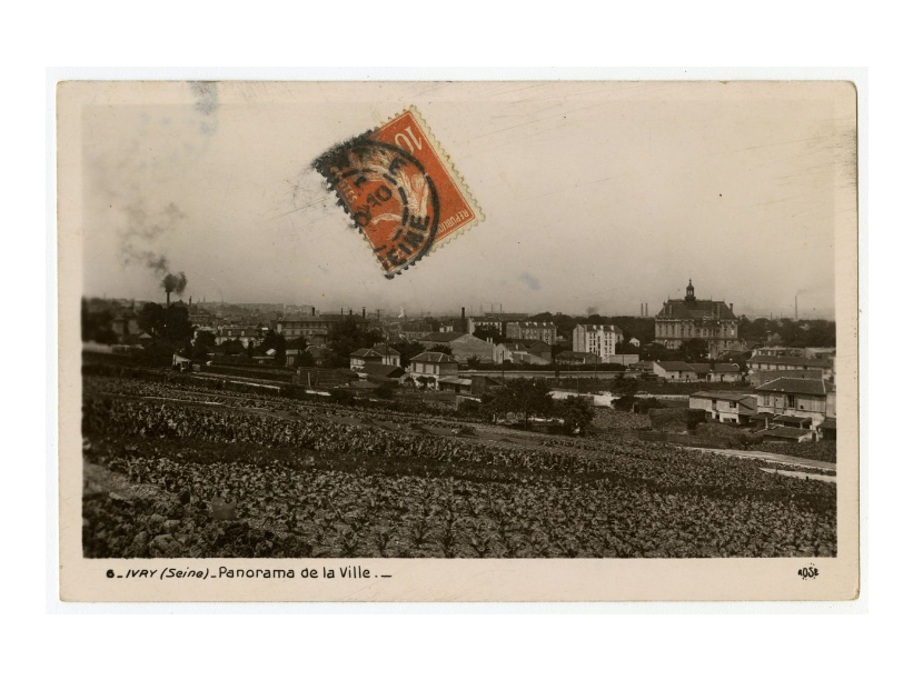 A black and white photograph of a field of crops that overlooks the outskirts of a large town or small city. On top of the photograph is a red stamp with black circular markings over it. At the bottom of photograph the text says &ldquo;6 IVRY (Seine) Panorama de la Ville.&rdquo;