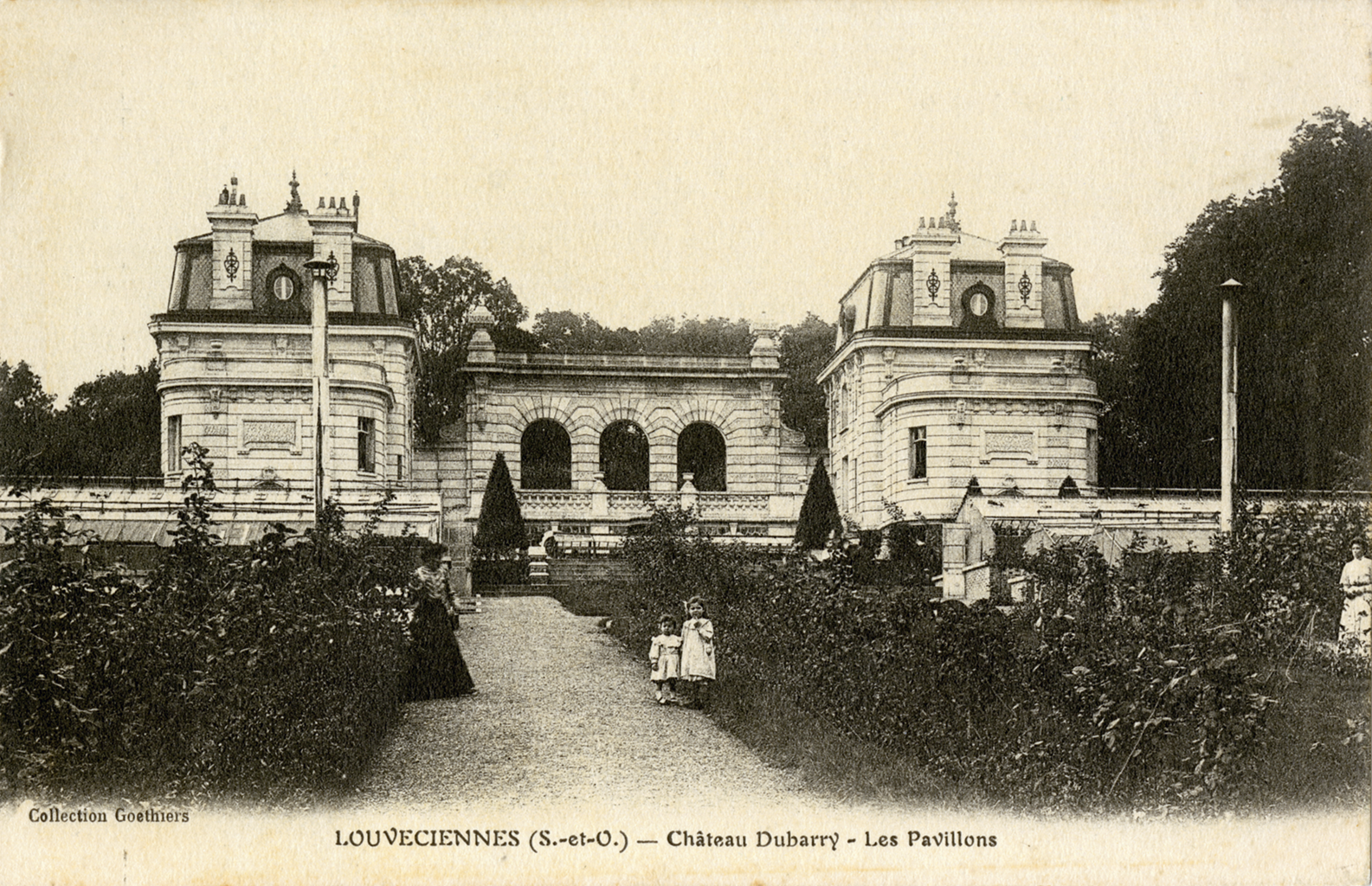 A sepia photograph of the facade of a large stone manor with three large archways and a porch. In front is a garden full of overgrown plants and bushes. Also, two women and two children who are wearing white clothing stand on a gravel path cutting through the garden.At the bottom it states &ldquo;Collection Goethiers&rdquo; &ldquo;LOUVECEINNES (S.-et-O.) Chateau - Dubarry - Les Pavillons&rdquo;