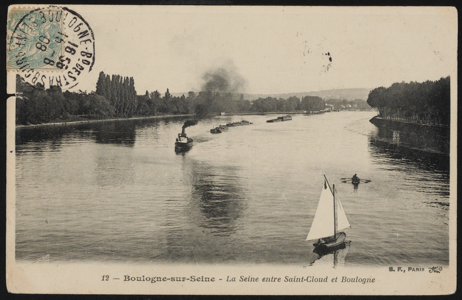 A black and white photograph of a wide river with a sailboat on the right-hand side. Near it is a smaller boat being pushed by two figures rowing their oars. In the middle of the river, there is a tugboat pulling three platforms down the it. Along the river is a trail will tall trees along the riverbank. A stamp light blue stamp is on the corner of the photograph. At the bottom of the image, it says &ldquo;Boulogne-sur-Seine—The Seine between Saint-Cloud and Boulogne.&rdquo;