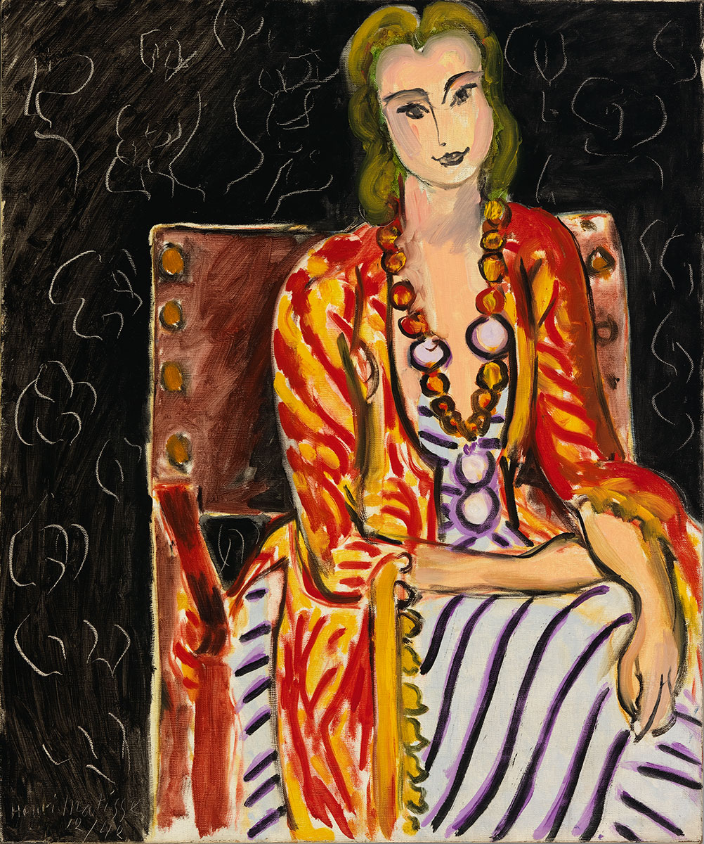 A woman seated in a brown chair wears a yellow and red striped fringed shawl over her white gown with black and violet stripes.