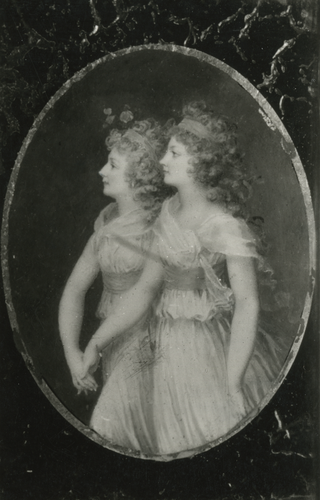 A black and white reproduciton of a drawing of two women walking and holding each other's hands. They both face to the viewer's left and have long, curly hair tied up with ribbons.
