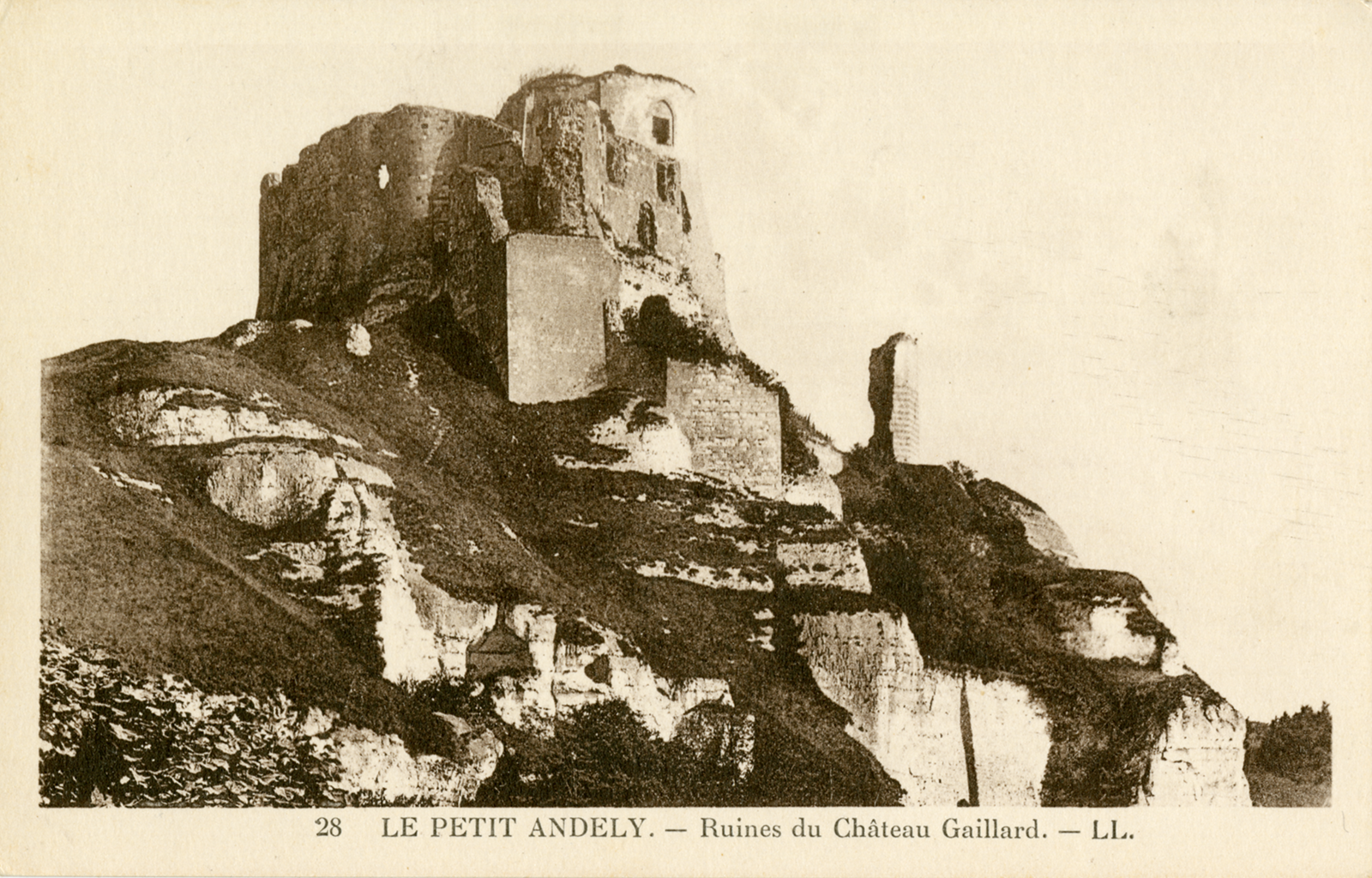 A sepia photograph of a rocky hill with the ruins of a building or chatue standing at the top. The bottom text states &ldquo;28 LEPTIT ANDELY. – Ruines du Chateau Gaillard&rdquo;