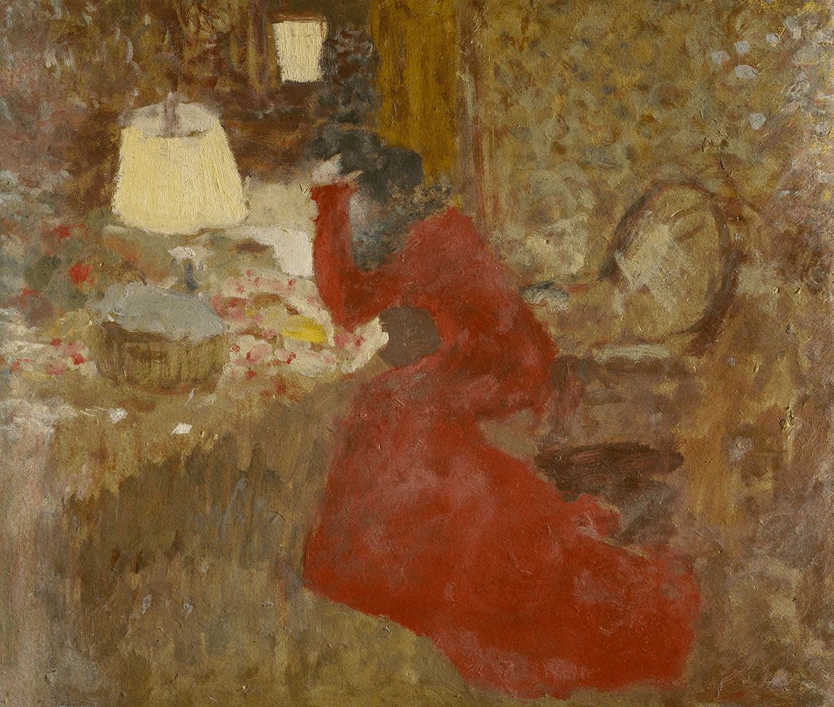 A solitary female figure in profile in a red dress is perched on the edge of an armchair. Head in hand, she hunches over a table with a lamp and basket.